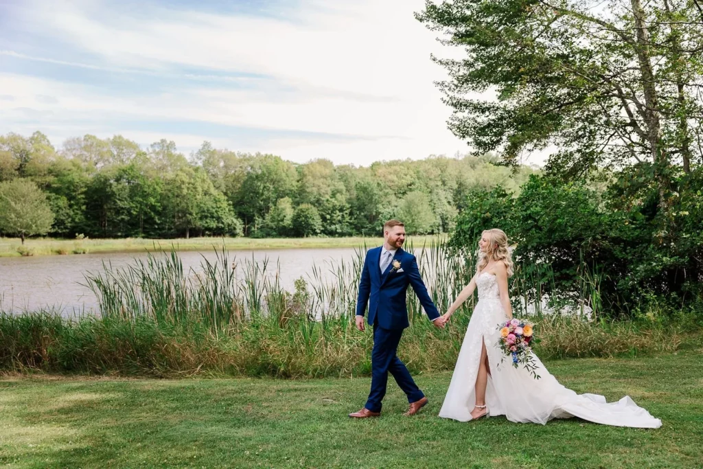 groom escorts bride along the waterfront at Wallkill Golf Club wedding venue