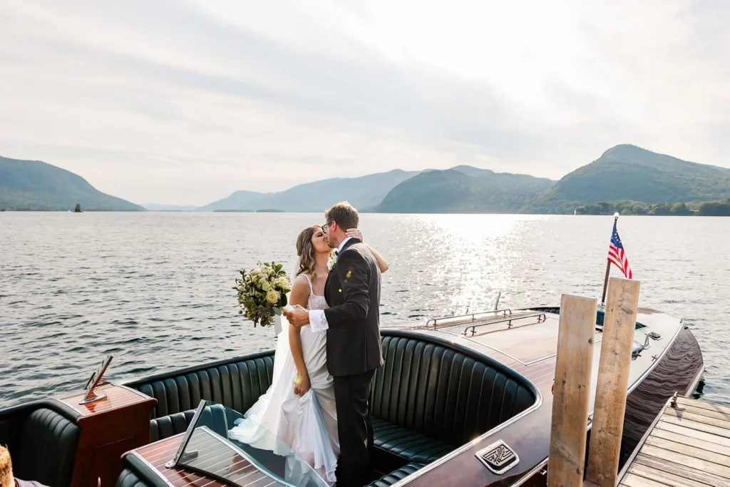 bride and groom kiss standing in boat on Lake George, NY