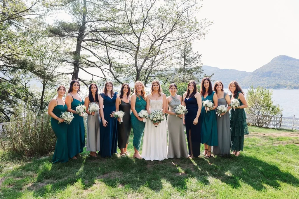 bride posed with wedding party wearing shades of blue and green